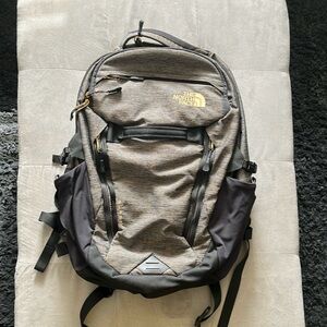 The North Face Surge Backpack. (Color - Greyish-Brown, Black with Gold accents)